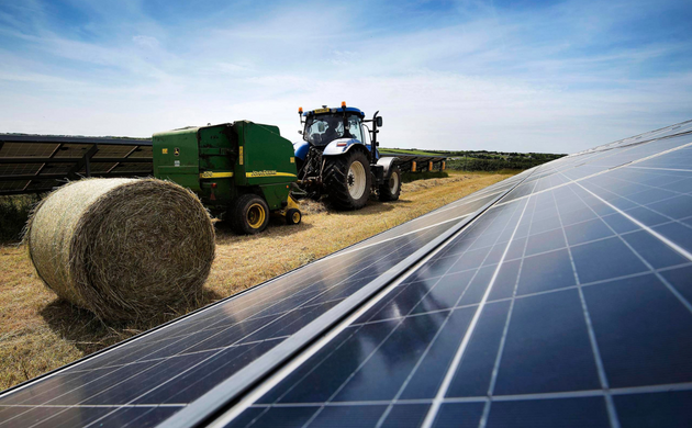 Tractor bailing between solar panels