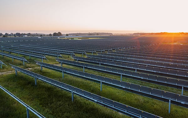 Golden-hour shot of the Lightsource bp Conway Solar project in Arkansas, showcasing vast, neatly aligned solar arrays stretching across green fields. As a key US Projects site, it reflects large-scale renewable energy development integrated with rural landscapes under a warm, setting sun.