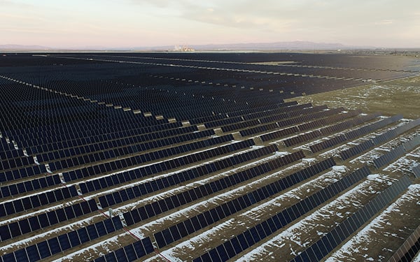 Aerial view of the Lightsource bp Sun Mountain Solar Farm in Colorado, part of their US Projects portfolio, rows of panels stretch across snow-dusted fields under a soft sunset sky.