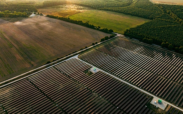 Vast solar power plant at sunset, showing the large scale of ground-mounted solar energy generation and its integration into the surrounding farmland.