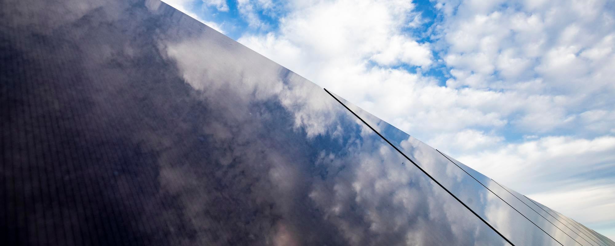 blue sky and clouds reflecting off a solar panel