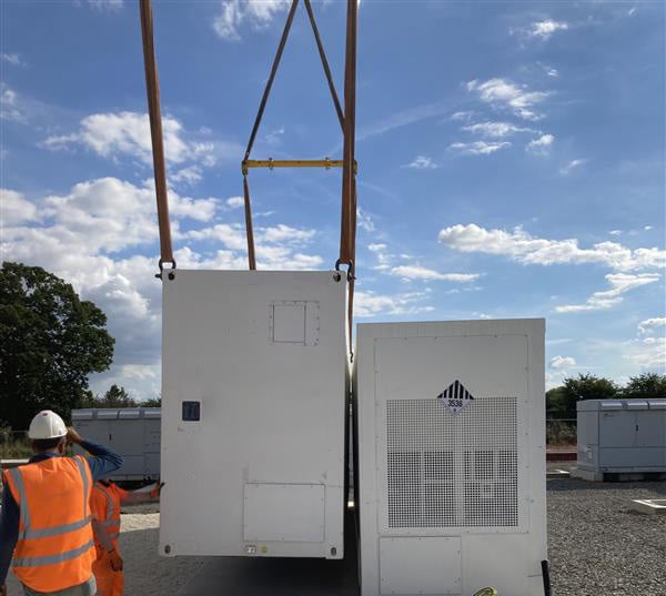 Installation of containerized solar inverter or BESS (Battery Energy Storage System) unit using heavy construction equipment.