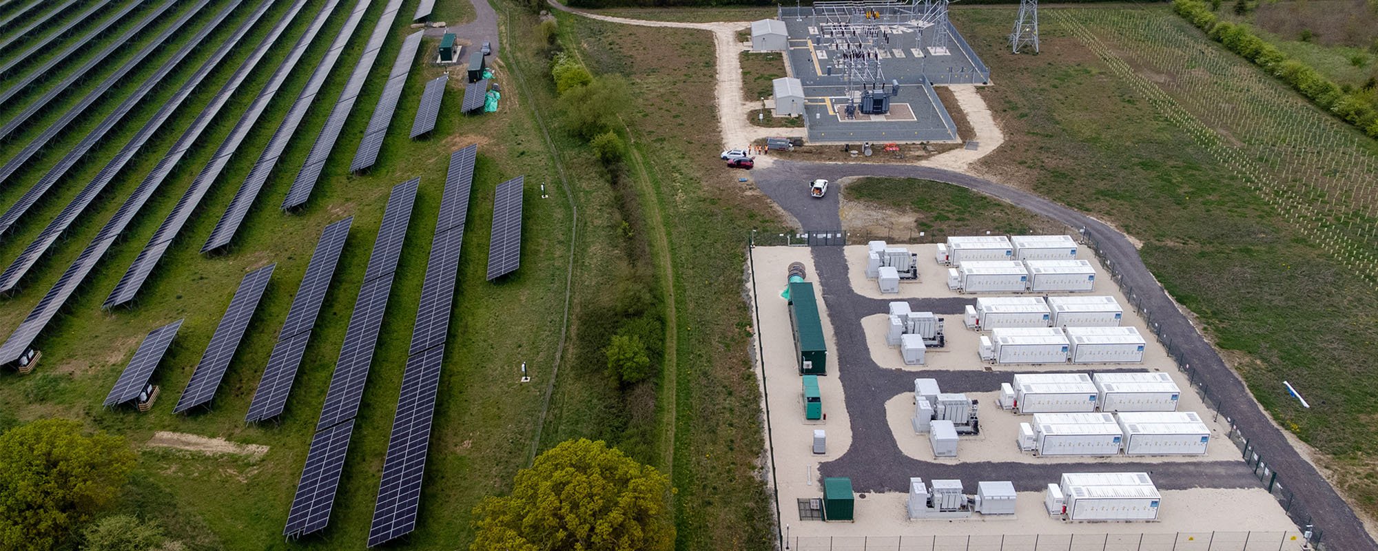 Aerial view of the Lightsource bp Tiln Energy Storage Project in the UK, part of their UK Projects portfolio, showing expansive solar arrays on grassy fields alongside a dedicated battery storage facility with white containers and substation infrastructure.