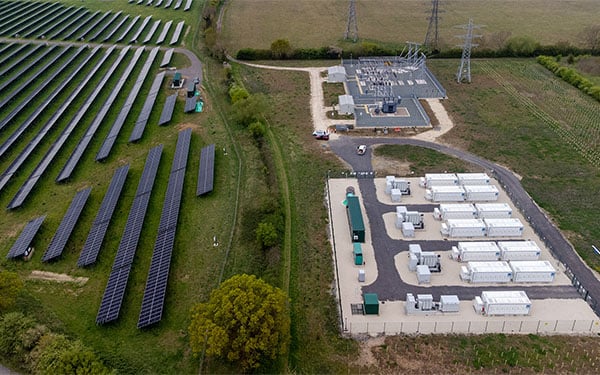 Aerial view of the Lightsource bp Tiln Energy Storage Project in the UK, part of their UK Projects portfolio, showing solar panels on grassy fields alongside a battery storage facility with white containers and substation infrastructure.