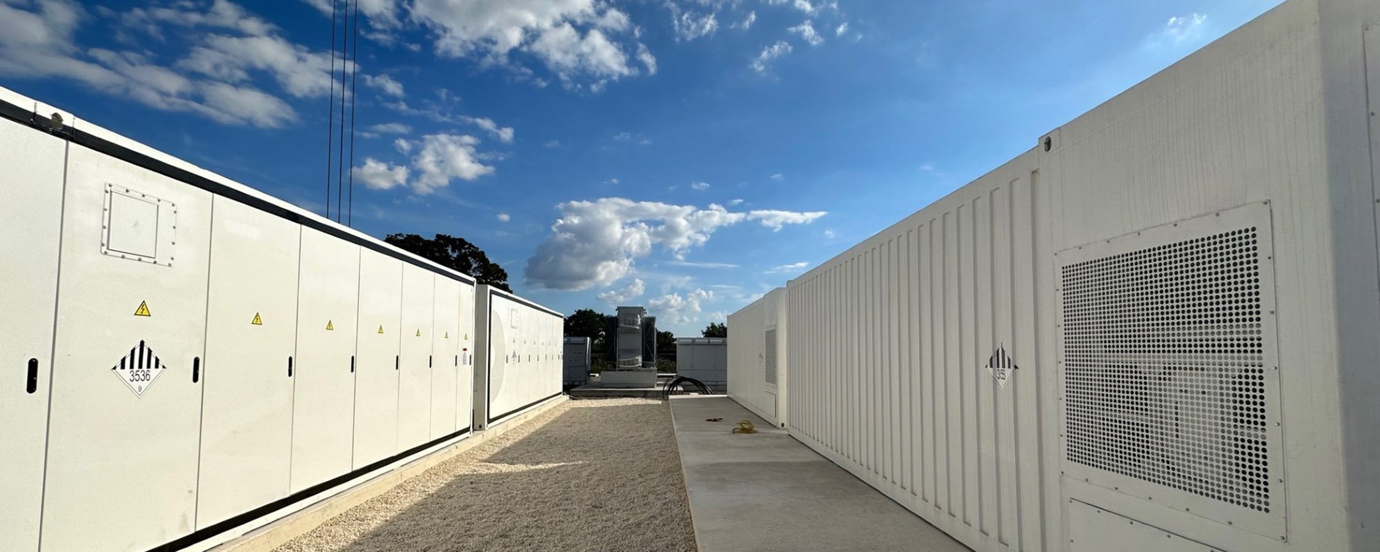Outdoor view of a utility-scale battery energy storage system (BESS) composed of large white containers