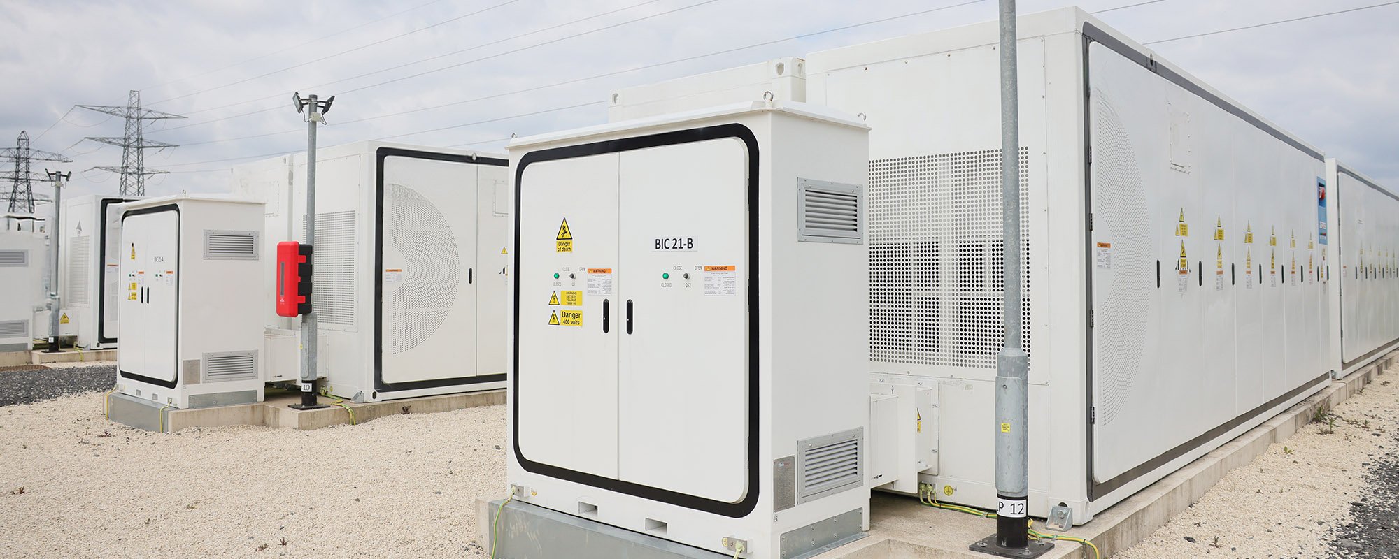 Utility-scale Battery Energy Storage System (BESS) with rows of white container units and inverter cabinets