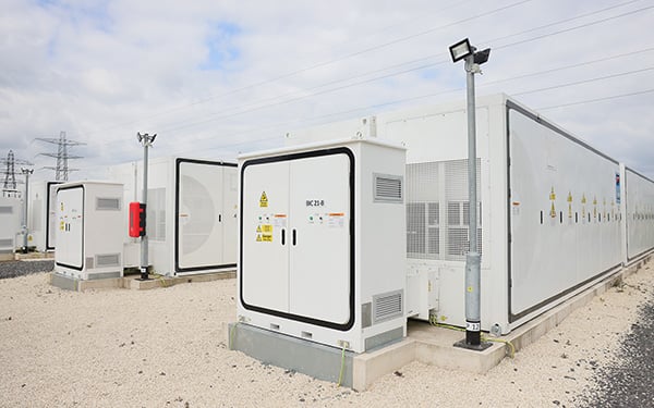 Utility-scale Battery Energy Storage System (BESS) with rows of white container units and inverter cabinets