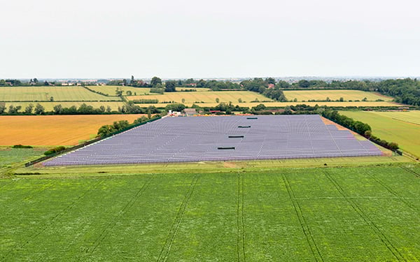 Aerial view of the Lightsource bp Wilburton solar farm in the UK, part of their UK Projects portfolio, rows of panels installed across green fields under a clear sky.