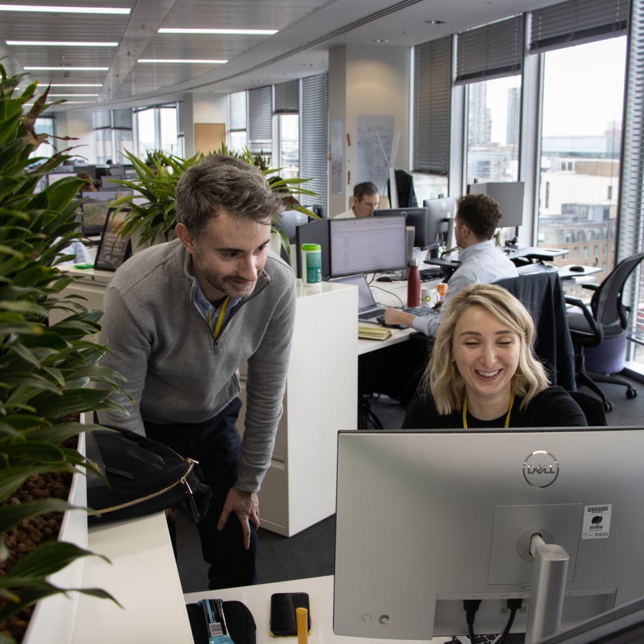 Two office workers working in an office in front of a monitor