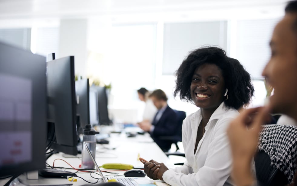 An office worker smiling to a coworker at their desks