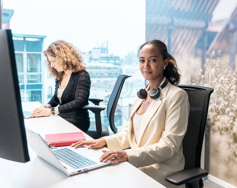 Two female office workers working by their desks