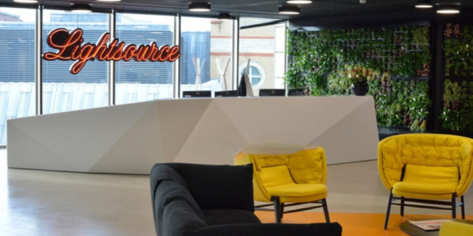 A photo of the Lightsource BP office, showcasing a modern and inviting workspace with comfortable seating, a reception area, and a vibrant green wall.