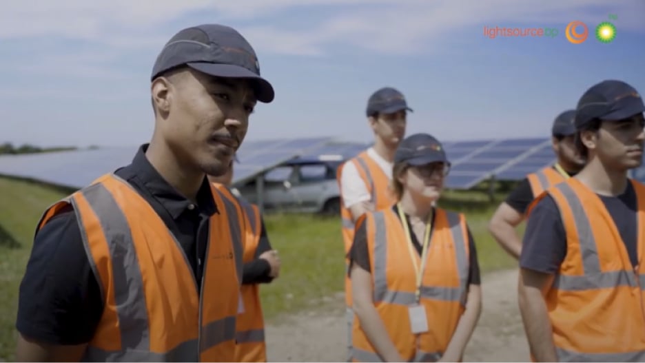 A group of people wearing PPE standing in a solar farm