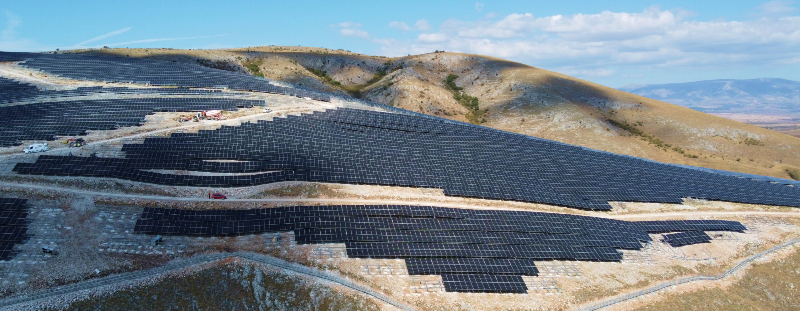 Aerial view of a large-scale solar farm built on a hillside, showcasing rows of solar panels generating clean energy.