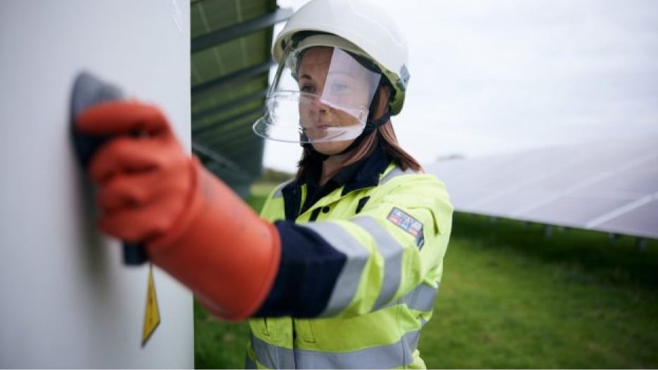 Person in PPE and wearing protective head gear grabbing a handle