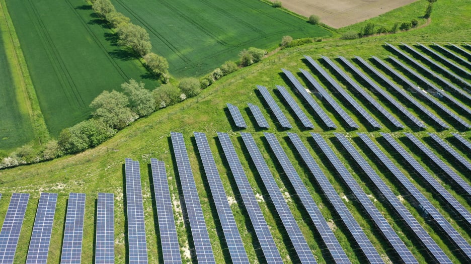 Aerial view of a solar farm integrated into a natural landscape, showcasing a harmonious coexistence of renewable energy and agriculture.