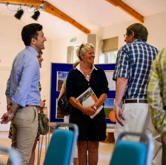 Group of people standing in a hall chatting to each other