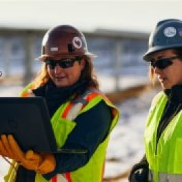 Two people in PPE gear looking at a laptop