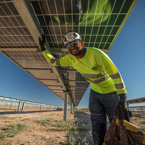 A construction worker in full PPE underneath a solar panel