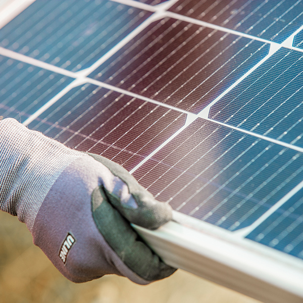 A gloved hand holding a solar panel