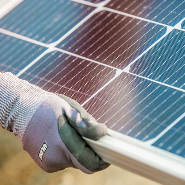 A gloved hand holding the edge of a solar panel