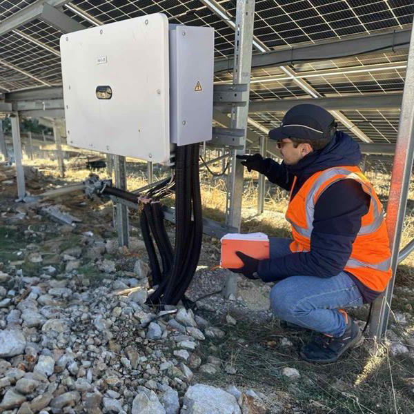 Diogo Costa in full PPE looking at the inverter under a solar panel