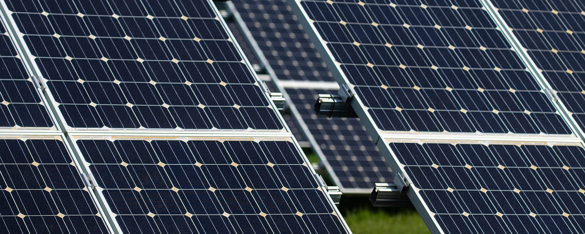 Close-up of solar panels at a Lightsource bp solar project, showing the grid pattern and metal framing under bright sunlight.