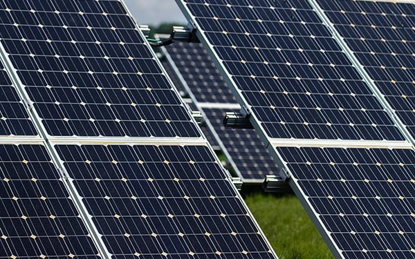 Close-up of solar panels at a Lightsource bp solar project, showing the grid pattern and metal framing under bright daylight.