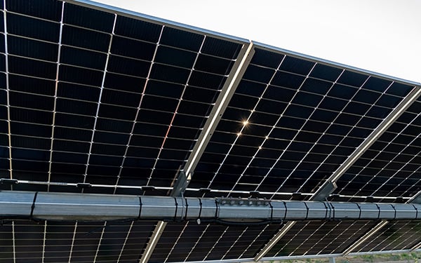 Close-up of solar panels at a Lightsource bp solar project, showing the grid pattern and metal framing under bright sunlight.